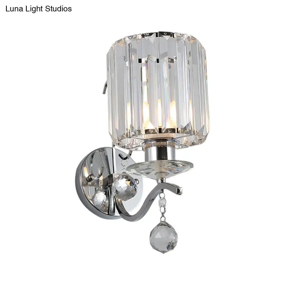 A modern chrome cylinder wall light fixture with clear crystal shade and dangling cut-glass pendant for bedroom lighting