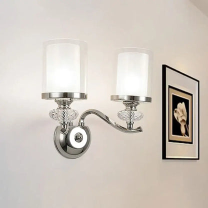 Modern chrome dual cylinder bathroom sconce with curvy arm, frosted glass shades, and crystal accents fixture height visible