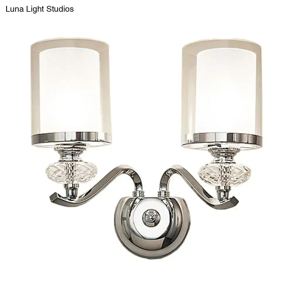 Modern chrome dual cylinder bathroom sconce with curvy arm, frosted glass shades, faceted crystal accents, and fixture height details