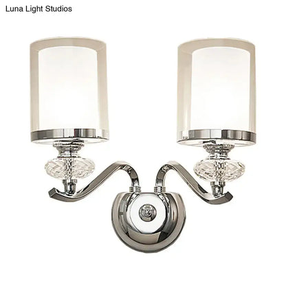 Modern chrome dual cylinder bathroom sconce with curvy arm, frosted glass shades, faceted crystal accents, and fixture height details