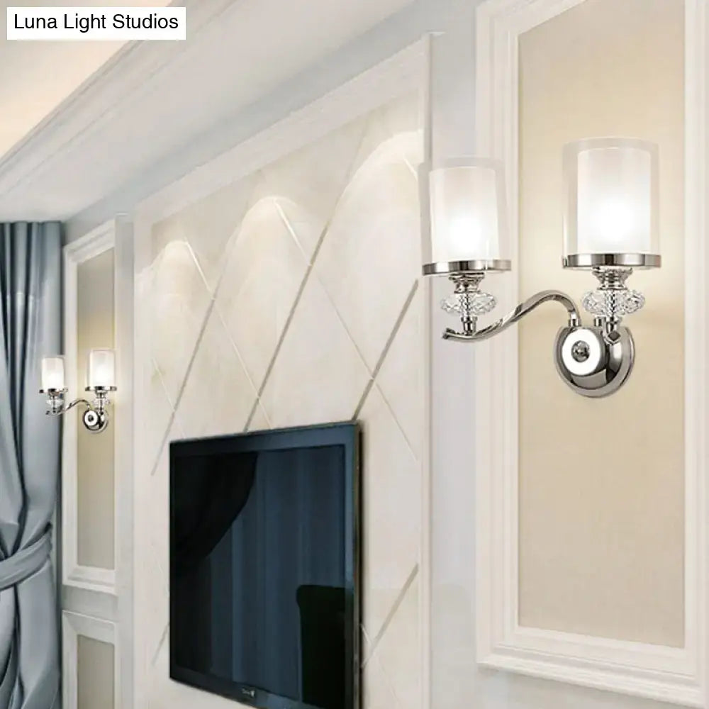 Silver two-light bathroom wall sconce with dual cylinder frosted glass shades and curvy arm fixture height design
