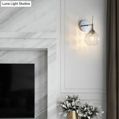A modern chrome finish wall lamp with a polished chrome finish and crystal inner glass for bedroom lighting