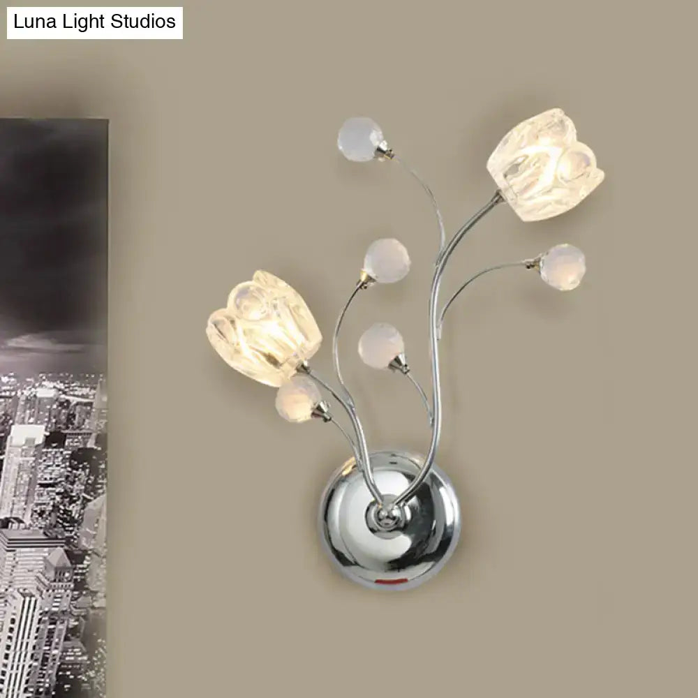 Modern chrome wall lamp with swirling arm, three illuminated glass flower shades, and four frosted crystal orbs