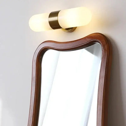 Warm-toned cylindrical vanity mirror light with frosted glass shades and brass-finished metal band for bathroom use