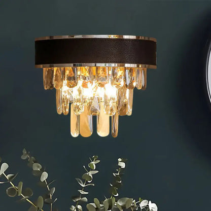A modern sconce light fixture with black leather band, chrome trim, and cascading golden crystal block teardrops wall lamp