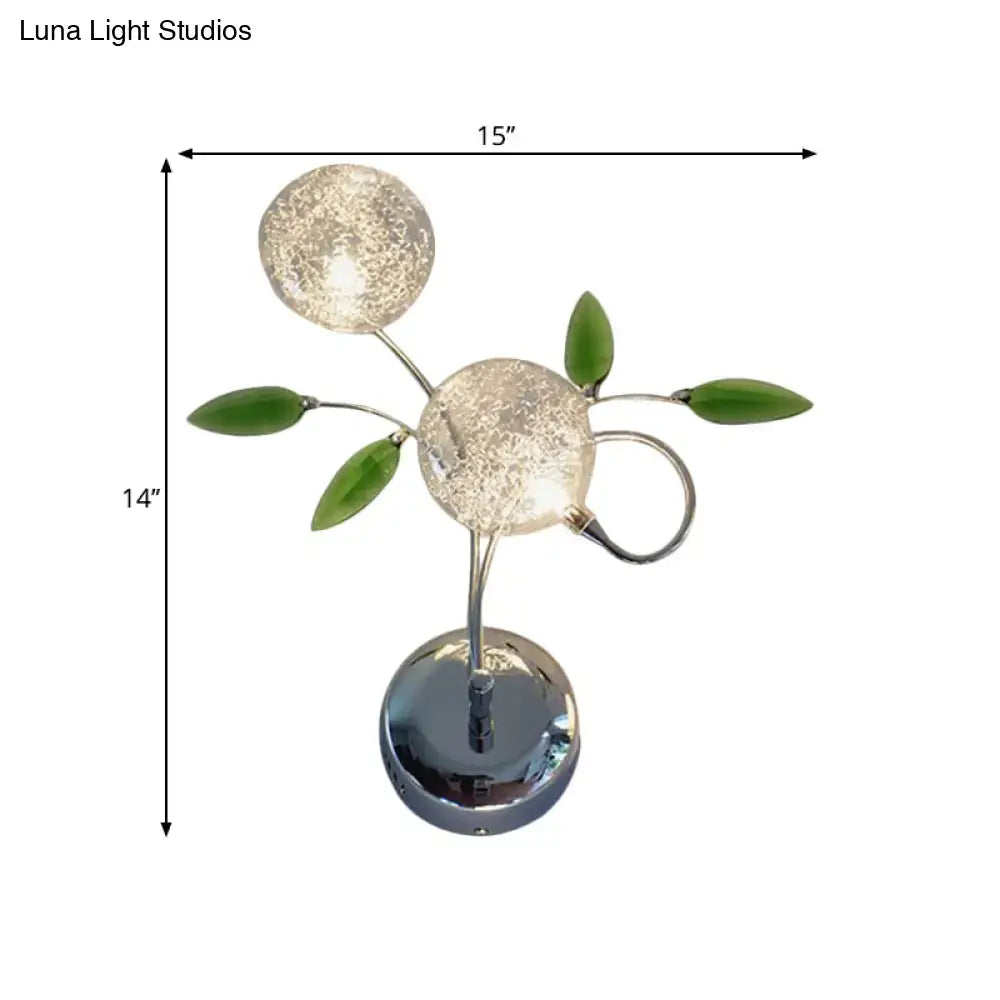 A modern chrome green crystal leaf wall mount lamp with frosted glass globes and decorative leaf accents