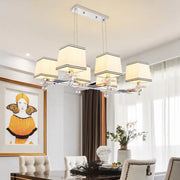 Modern chrome island pendant light with five cream fabric shades and black trim in a sleek pendant light kit design