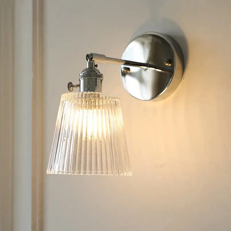 A modern chrome wall lamp with a clear ribbed glass shade diffusing warm light for dining room decorbites clear glass