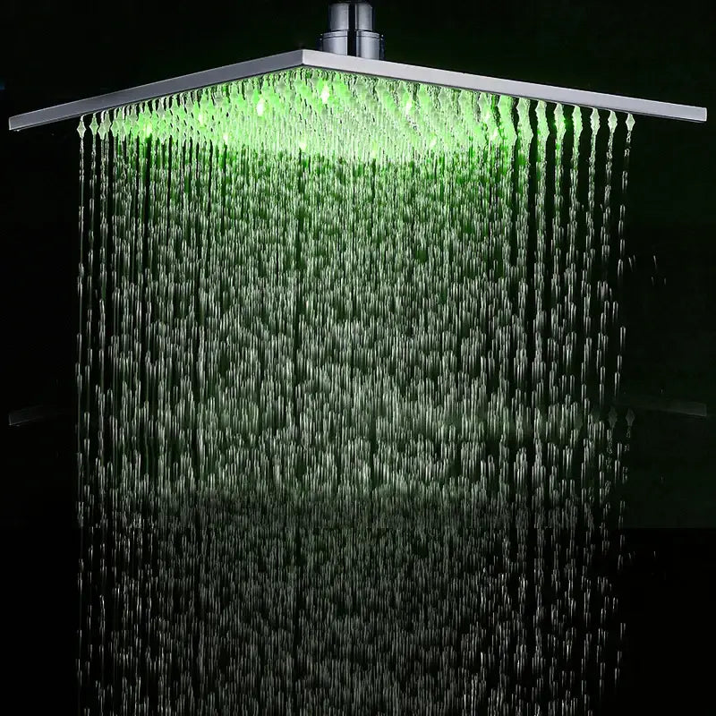 Modern chrome square rainfall shower head with led lights illuminating cascading water streams in bathroom faucet