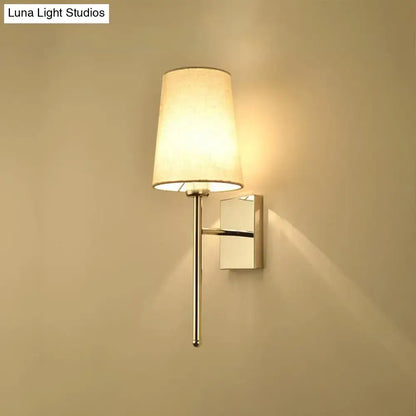 Modern chrome tapered wall sconce with a sleek chrome finish and off-white fabric shade for bedroom lighting