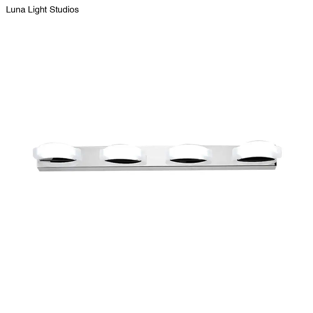 Modern chrome vanity mirror light with four frosted glass shades emits warm color temperature in white warm color