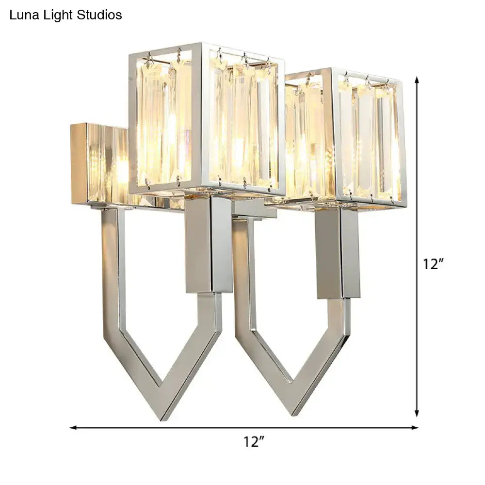 Modern chrome wall lamp with clear crystal rectangular panels and metal frames emitting warm glow for living room