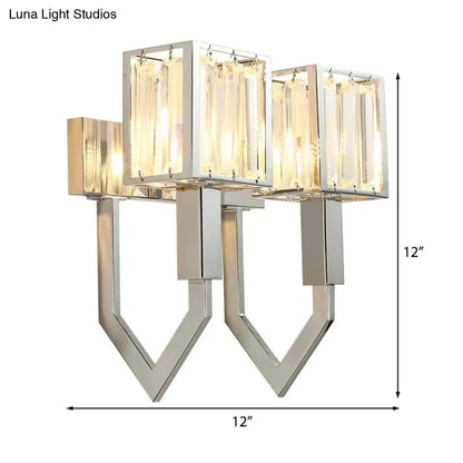 Modern chrome wall lamp with clear crystal rectangular panels and metal frames emitting warm glow for living room