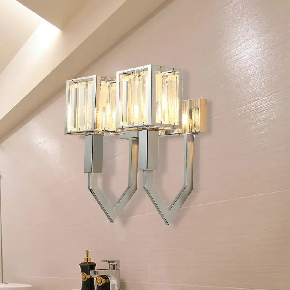Modern chrome wall lamp with clear crystal rectangular shades and metal frames emitting warm light for living room