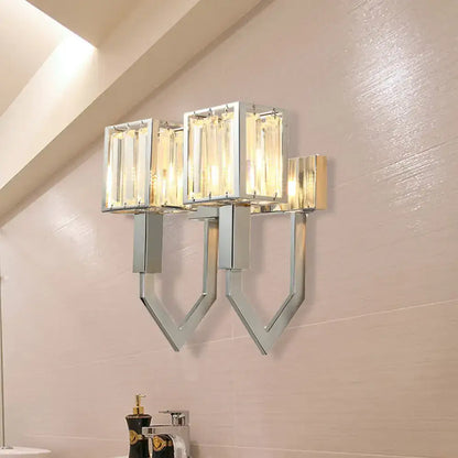 Modern chrome wall lamp with clear crystal rectangular shades and metal frames emitting warm light for living room