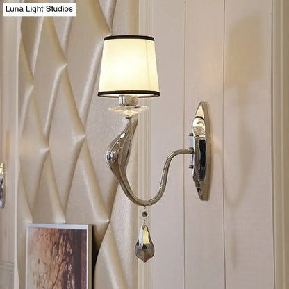 Modern chrome wall lamp with curved sculptural arm cream fabric shade with black trim for living room lighting