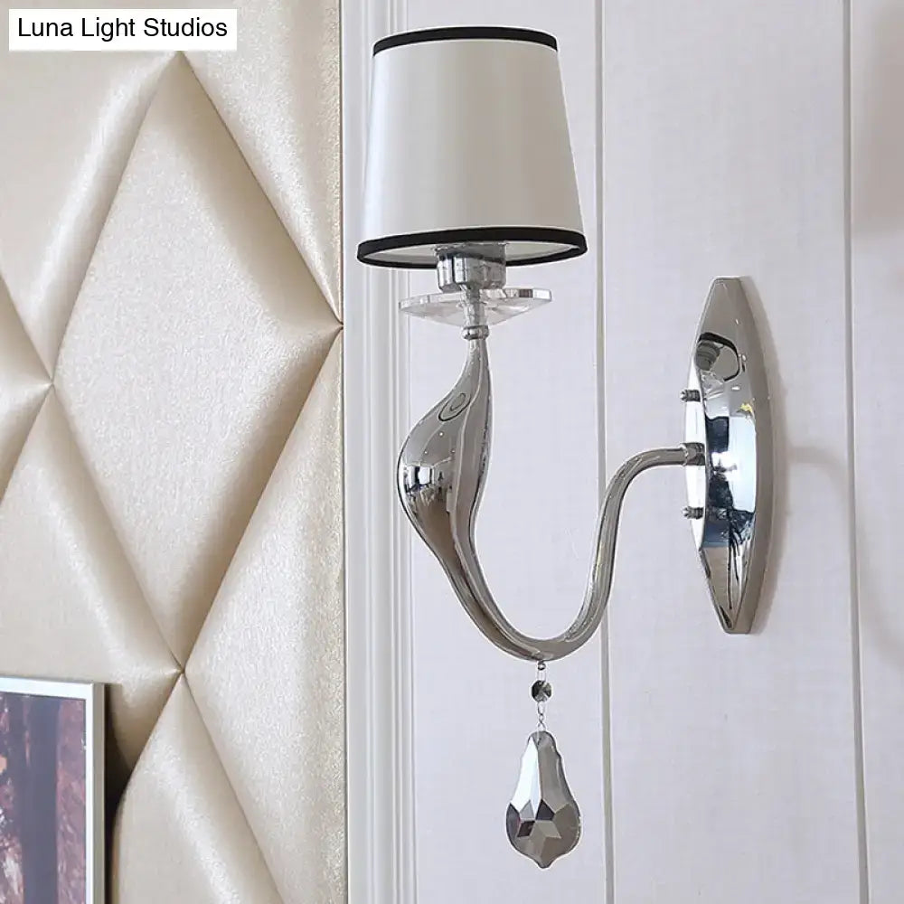 Modern chrome wall lamp with sleek curved arm and white fabric shade with black trim for living room use