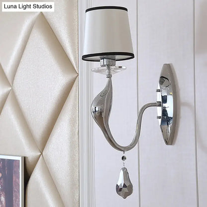 Modern chrome wall lamp with sleek curved arm and white fabric shade with black trim for living room use