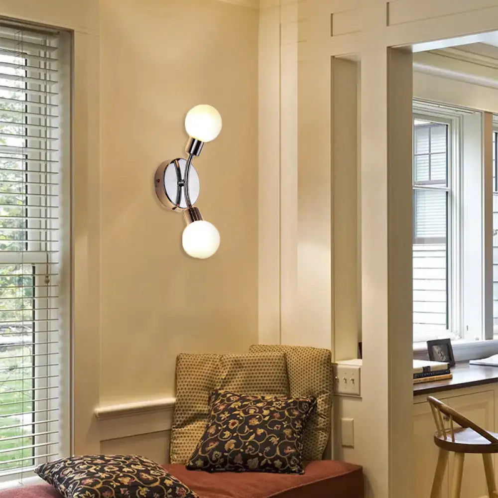 Modern chrome wall lamp with white glass fixture featuring two frosted glass bulbs and a sleek bulb base for bedroom use