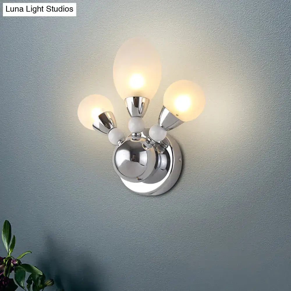 Modern chrome wall light with three frosted white glass globes and white marble accents for bedroom sconce lighting