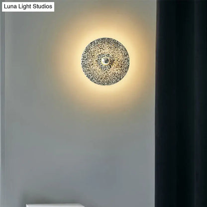 Modern circular terrazzo wall light in beige and lake blue with textured crystals and polished brass for corridors