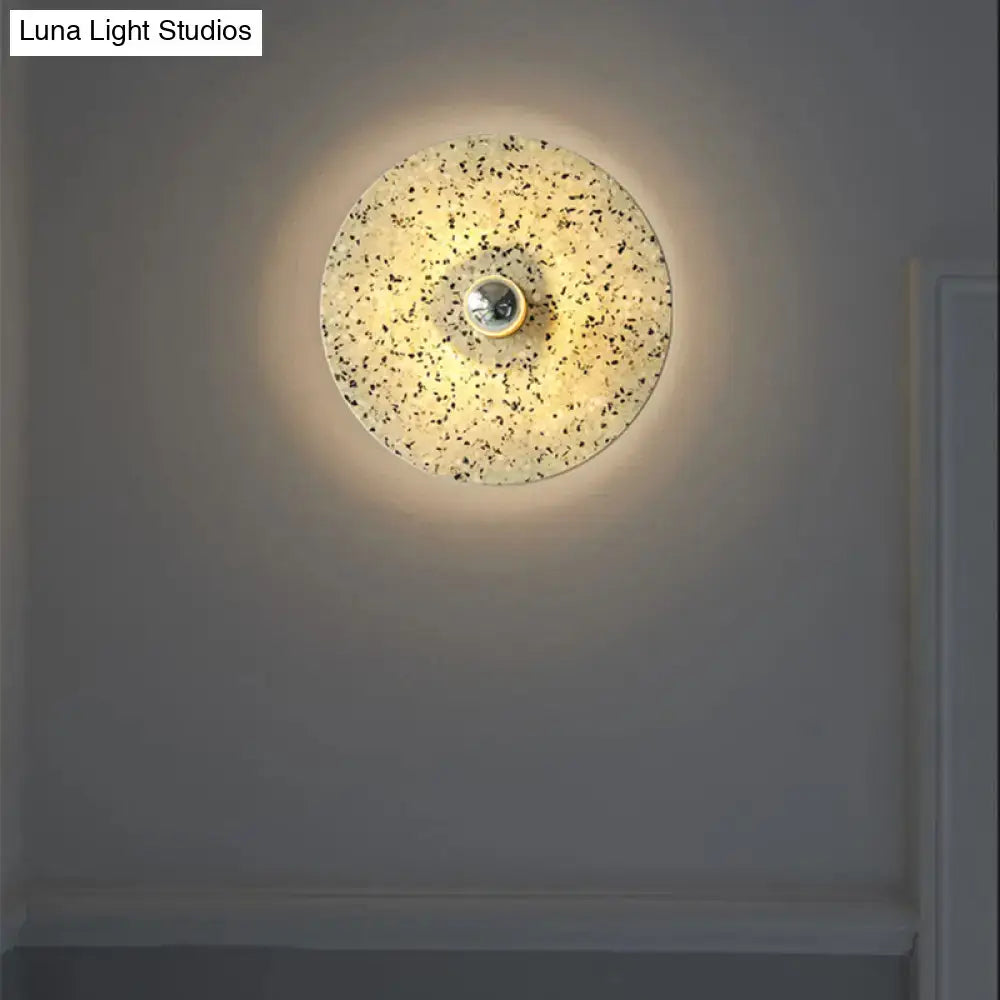 Modern circular terrazzo wall light in beige and lake blue with speckled finish and central metallic fixture for corridors