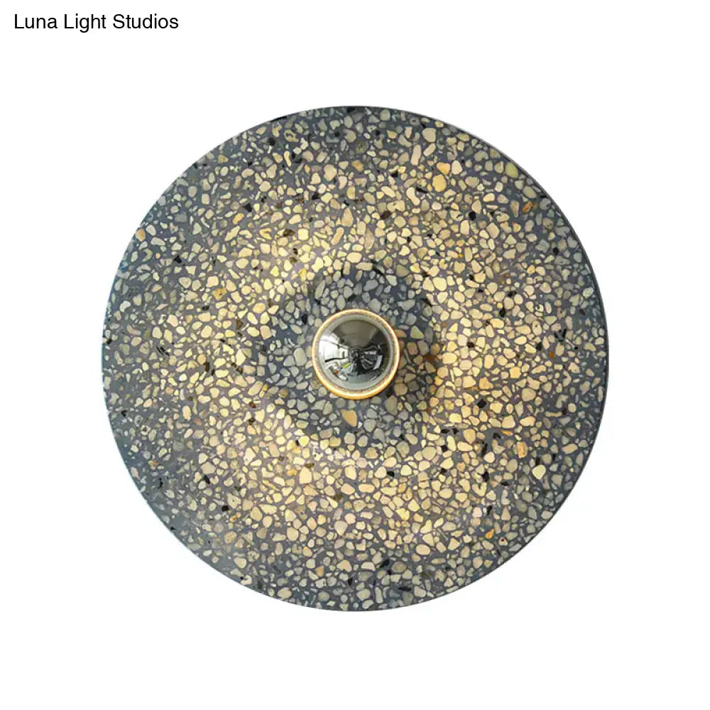Modern circular terrazzo wall light in beige lake blue with speckled gray and gold pattern and brass bulb socket