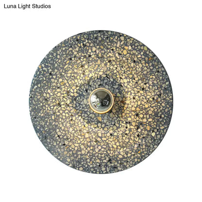 Modern circular terrazzo wall light in beige lake blue with speckled gray and gold pattern and brass bulb socket