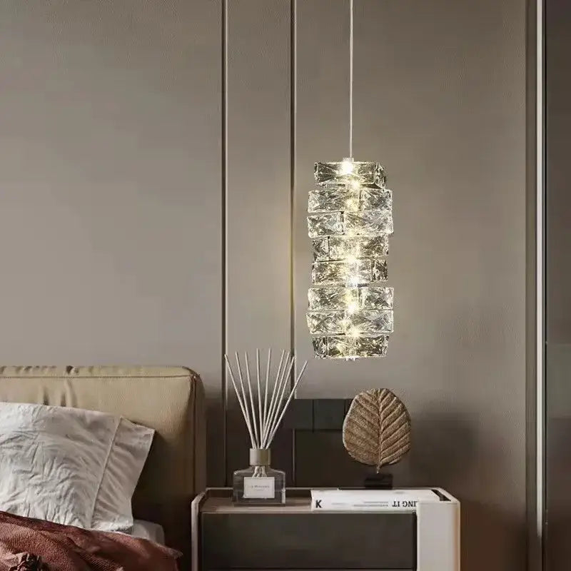 A modern circular textured crystal chandelier pendant light with stacked faceted glass segments emitting warm glow