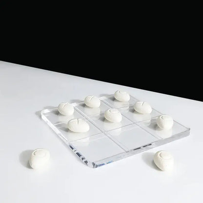 Modern clear acrylic tic tac toe board with white textured resin pebble chess pieces for living room decor