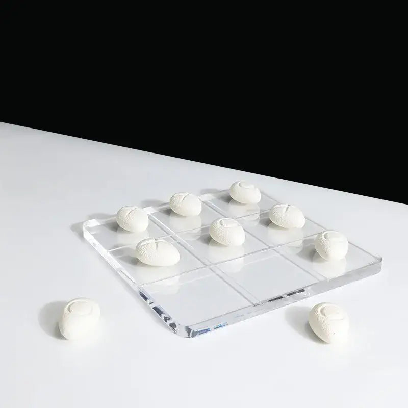 Modern clear acrylic tic tac toe board with white textured resin pebble chess pieces for living room decor