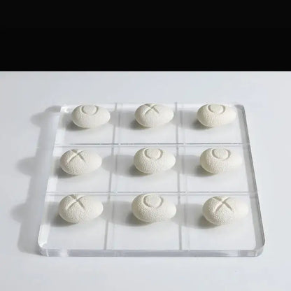 Modern clear acrylic tic tac toe board with white textured resin pebble chess pieces for elegant living room decor