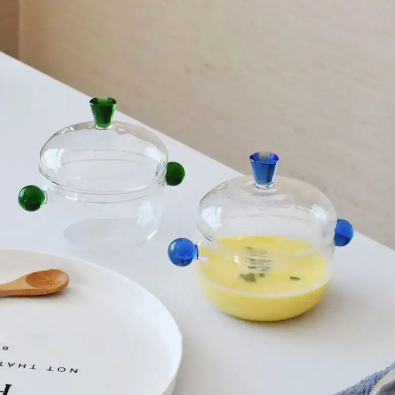 Modern clear and green glass bowl set with colorful spherical handles and lids perfect for kitchen simmer pot use