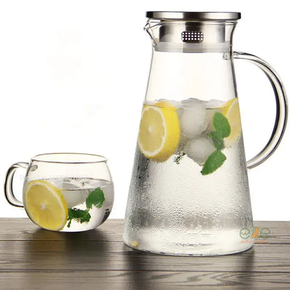 Modern clear borosilicate glass pitcher with stainless steel lid filled with ice lemon slices and mint leaves
