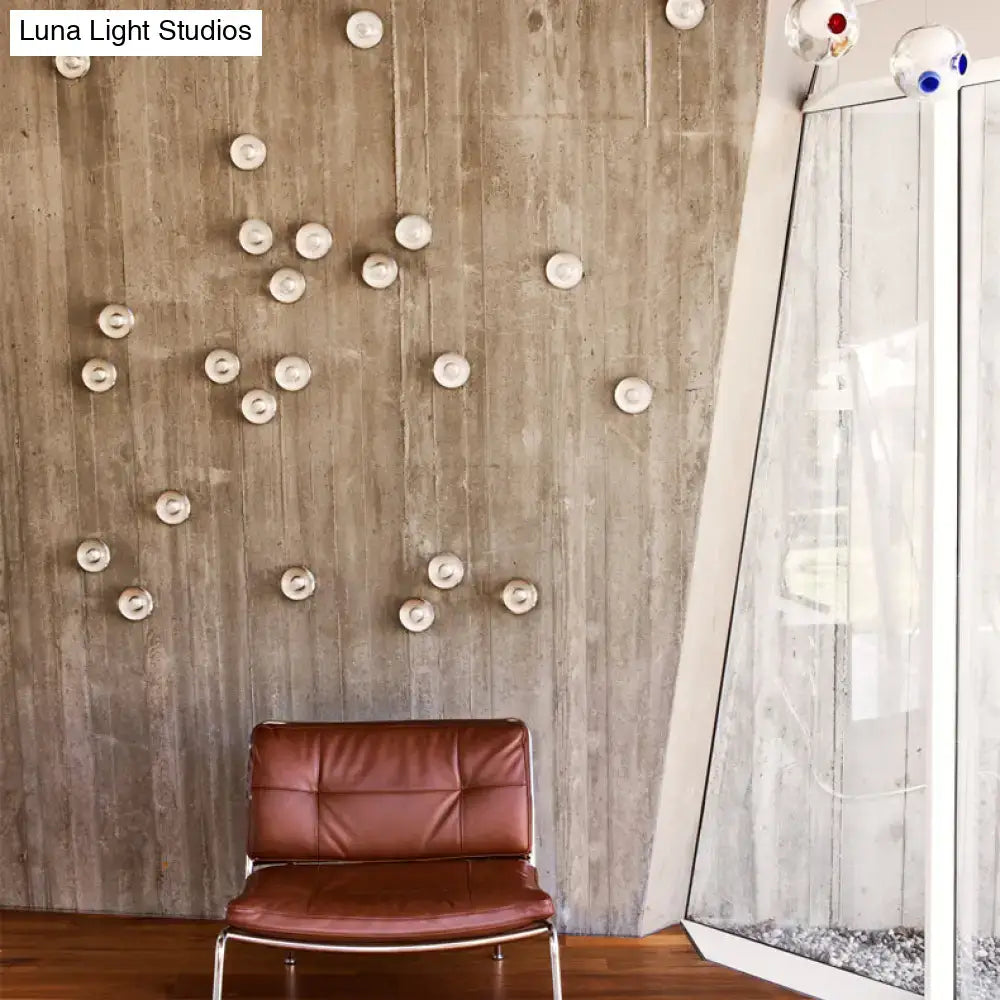 Brown leather chair with metal frame next to modern clear bubble crystal wall light in warm white for living room