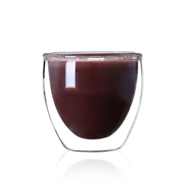 A modern clear double wall glass cup filled with dark brown liquid for dining room use