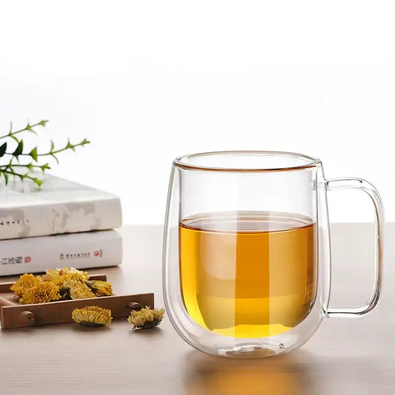 Modern clear double wall glass mug with handle filled with golden tea for kitchen use