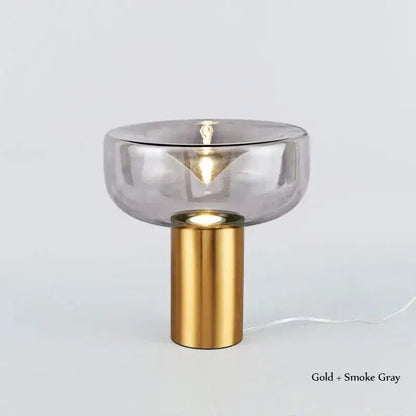 A sleek modern decorbites aella table lamp with a gold cylindrical base and smoke gray glass shade for bedroom decor