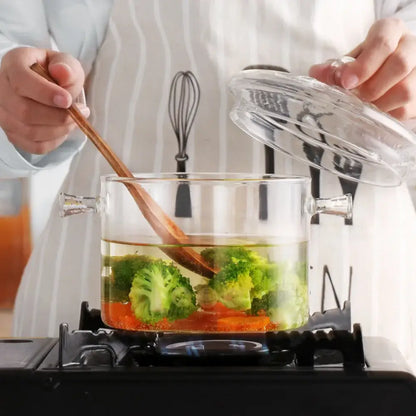Modern clear glass cooking pot with silver handles containing boiling broccoli and carrots in boiling water