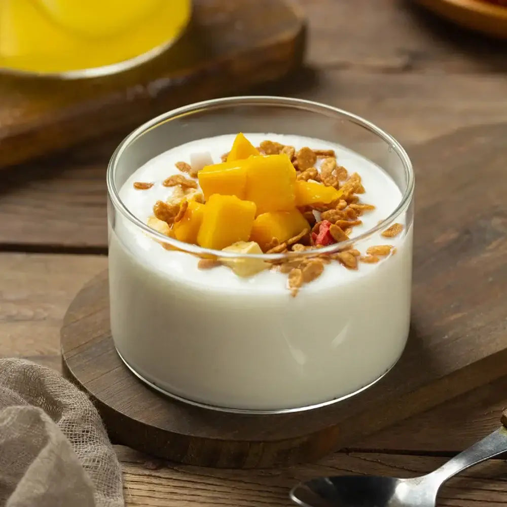 Modern clear glass cup set by decorbites showing a clear bowl with creamy yogurt, mango cubes, and granola topping