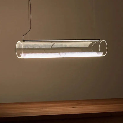 Modern clear glass cylinder pendant light with metallic mesh interior emitting warm white LED illumination for dining room