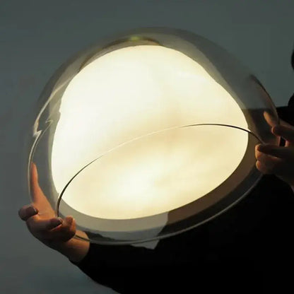 A sleek modern clear glass jelly pendant lamp with a warm diffused glow for living room and dining room