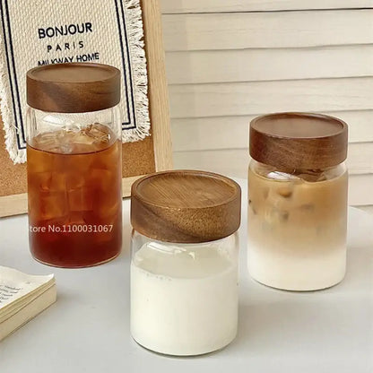 Three clear glass tea cups with wooden lids filled with colored iced beverages for modern kitchen use