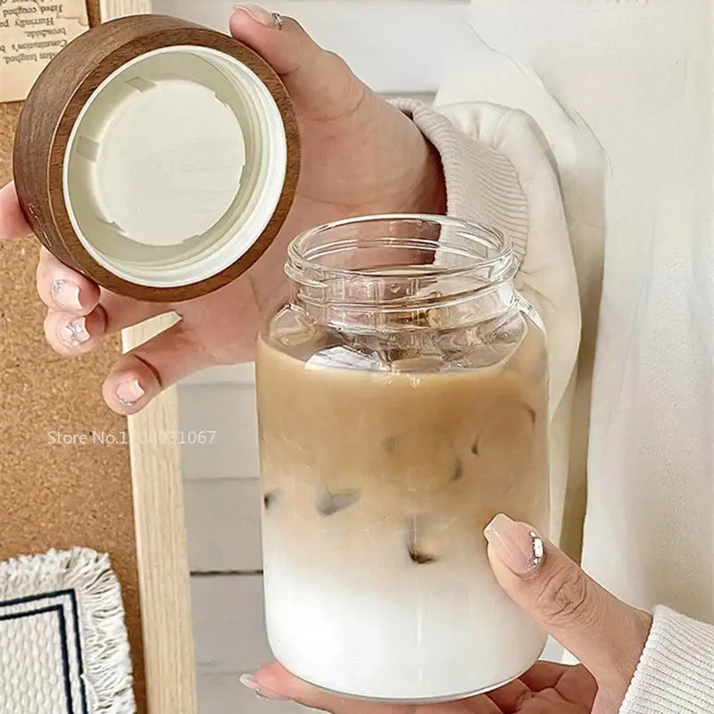 Modern clear glass tea cup with wooden lid filled with iced coffee as a versatile kitchen coffee jar