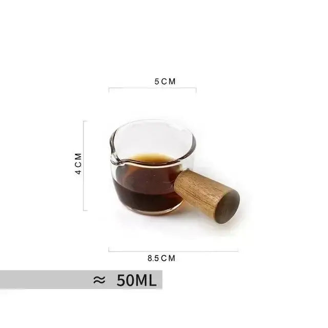 A modern clear glass tea cup filled with dark liquid featuring a wooden handle for kitchen use