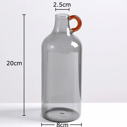 A modern clear glass vase with a tall translucent gray body and orange-tinted handle for living room decor
