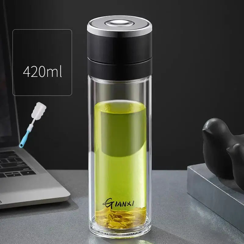 Modern clear insulated decorbites insulated glass cup with black silver lid holding green tea leaves in base