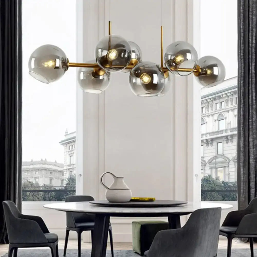 Modern chandelier lighting fixture with clear smoke glass globe shades and brass-colored bar for dining room use