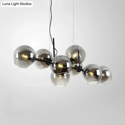 Modern black metal lighting fixture with eight clear smoke glass spheres for dining room use in black and gold finish
