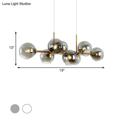Modern brass-finished lighting fixture with clear smoke glass globe shades in black and gold for dining room use